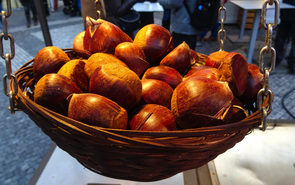 kleiner Korb mit gerösteten Kastanien, die auf dem traditionellen Weihnachtsmarkt auf dem Altstädter Ring verkauft werden, Prag