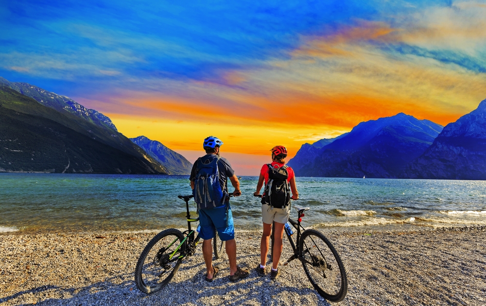 Mountainbiken, Paar mit Fahrrädern bei Sonnenuntergang am Gardasee, Riva