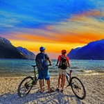 Mountainbiken, Paar mit Fahrrädern bei Sonnenuntergang am Gardasee, Riva