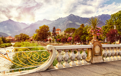 Blick über Fluss und Brücke vor Bergen, bei Sonnenuntergang und blauem Himmel.