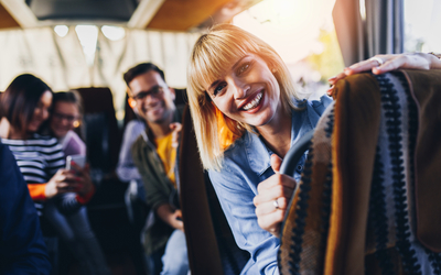 Personen lächeln und gestikulieren in einem Reisebus.