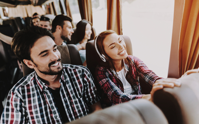 Junges lächelndes Paar reist in einem Touristenbus.
