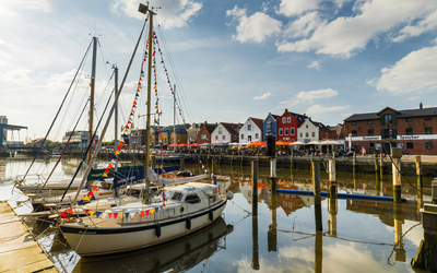 Segelboote im Hafen von Husum, umgeben von traditioneller Architektur und mit Blick auf die Nordsee.