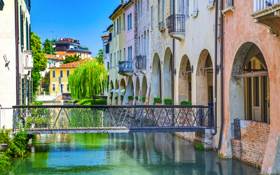 Bunte Häuser an einem Kanal mit Brücke in einer italienischen Stadt.