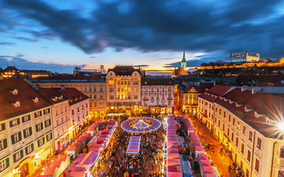 Blick auf einen belebten Marktplatz bei Dämmerung mit rot-weißen Marktständen