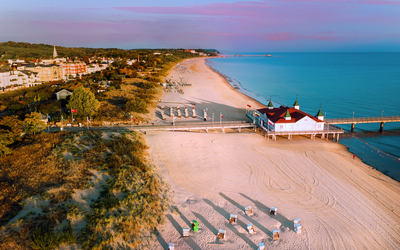 Luftbild einer Küste mit Strand, Promenade und Strandkörben bei Sonnenuntergang