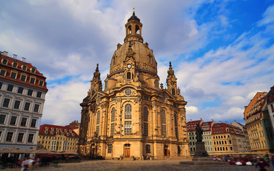 Barocke Kirche auf einem Platz bei blauem Himmel und umliegenden Gebäuden