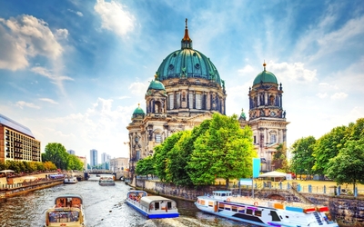 Berliner Dom mit Booten auf der Spree bei sonnigem Himmel.