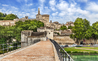 Brücke in Avignon mit altem Gebäude im Hintergrund an einem sonnigen Tag.