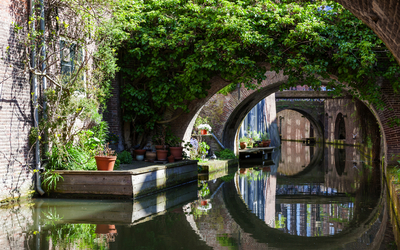 Kanal mit Brücken und Pflanzen, sonniger Tag, ruhiges Wasser.