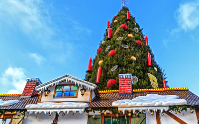 Dekorierter Weihnachtsbaum auf einem Weihnachtsmarkt mit blauem Himmel.