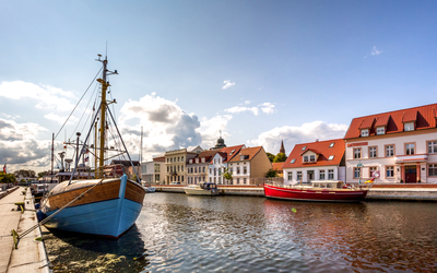 Historische Gebäude und Boote im Hafen an einem sonnigen Tag.