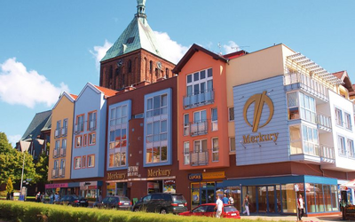 Bunte Häuserreihe und Kirchturm bei Sonnenschein in der Innenstadt von Köslin.