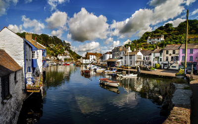 Malerischer Hafen mit Booten und Häusern unter bewölktem Himmel.