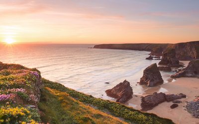 Küste bei Sonnenuntergang mit Felsen und Sandstrand.