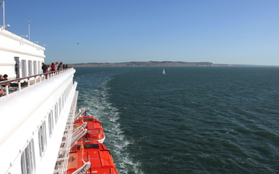 Blick von einem Schiff auf die Küste und das Meer mit klarem Himmel.