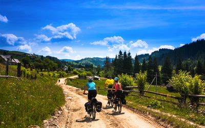Drei Radfahrer auf einem ländlichen Weg bei sonnigem Wetter.