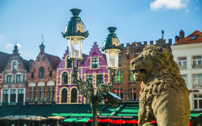 Steinlöwe und Laterne vor bunten Häusern in einer Altstadt.