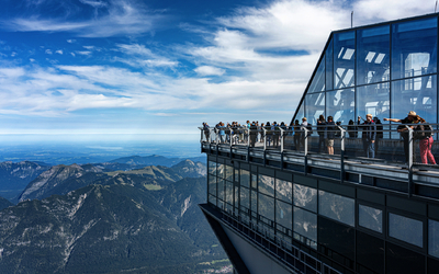 Menschen auf einer Aussichtsplattform in den Bergen mit weiten Blicken in die Landschaft.