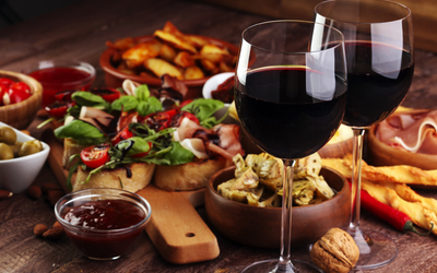 Tisch mit Rotweingläsern, Antipasti, Brot und Nüssen.