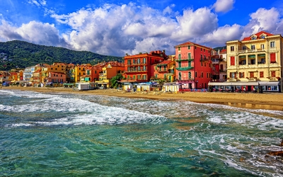 Bunte Gebäude am Meer mit bewölktem Himmel im Hintergrund.