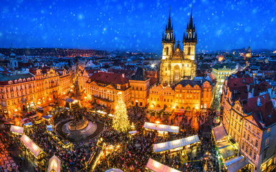 Vogelperspektive auf belebten Weihnachtsmarkt bei Nacht mit Kirche und Lichtern.