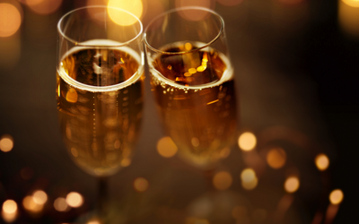 Zwei gefüllte Sektgläser mit unscharfem Bokeh-Hintergrund.