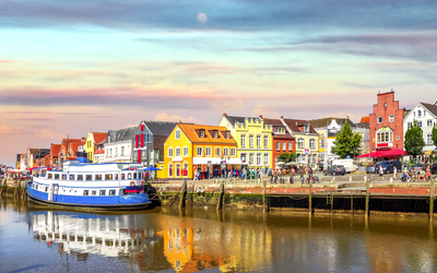 Bunte Gebäude am Flussufer bei Sonnenuntergang, mit Boot im Wasser.