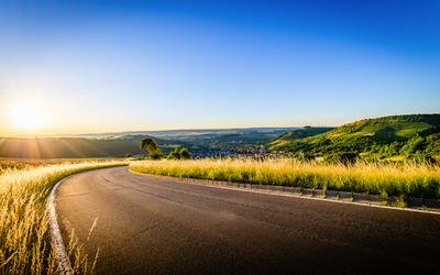 Landstraße durch hügelige Landschaft bei Sonnenaufgang