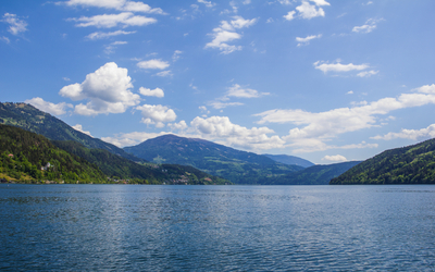 See mit umliegenden Bergen und blauem Himmel mit Wolken.