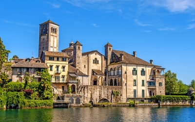 Historische Gebäude am Ufer eines Sees unter blauem Himmel.
