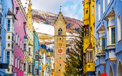 Bunte Häuserfassade und Turm in einer Alpenstadt im Winter.
