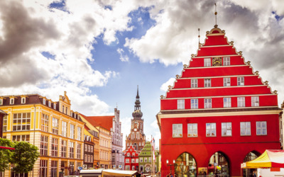 Historischer Marktplatz mit roten Giebelhäusern und Kirchturm im Hintergrund.