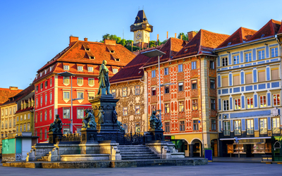 Hauptplatz in Graz mit Brunnen und umgebenden Gebäuden bei Tageslicht.