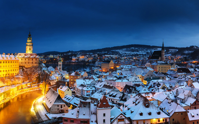 Verschneite Altstadt bei Abenddämmerung mit Kirchturm und Fachwerkhäusern.