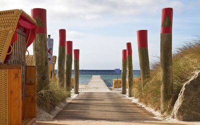 Promenade zum Strand mit Dünen, Holzpfählen und Strandkörben, Blick aufs Meer.