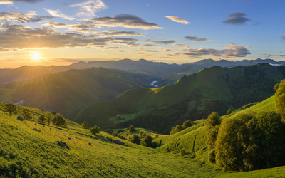 Sonnenuntergang über grünen Hügeln und Bergen.