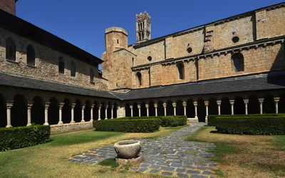 Innenhof eines Klosters mit begrüntem Garten und romanischer Architektur.