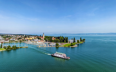 Luftaufnahme eines Schiffes auf einem großen See mit einer Stadt im Hintergrund