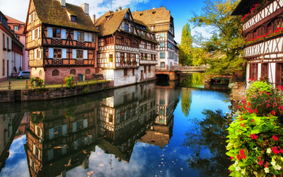 Fachwerkhäuser an einem Kanal in einer malerischen Altstadt mit Herbstlaub.