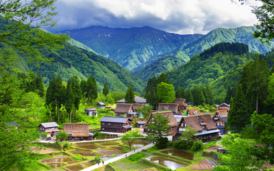 Japanisches Dorf in einem grünen Tal mit Bergen im Hintergrund
