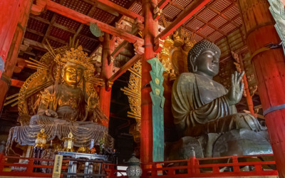 Buddha-Statuen in einem Tempel mit roten Holzsäulen.