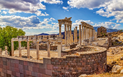 Ruinen eines antiken Tempels mit Säulen und Mauerwerk unter einem bewölkten Himmel.