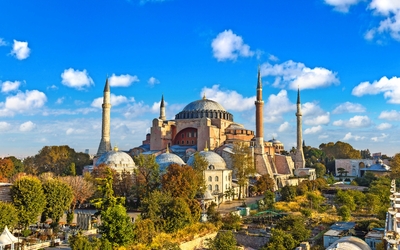 Historische Moschee mit vier Minaretten bei blauem Himmel.